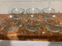 Six clear glass dessert bowls arranged on surface