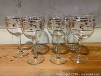 Set of six stemmed cordial glasses on wooden surface
