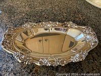 Top view of oval silver plate tray with ornate scroll rim