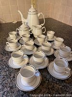Full set arranged on countertop showing all cups, saucers, coffee pot, creamer, sugar bowl