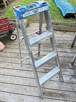 Full view of folded aluminum ladder showing three steps and top tray
