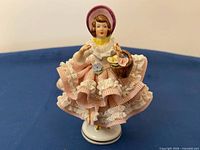 Front view of figurine showing lace dress, basket, bonnet