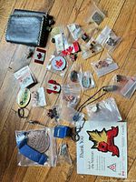Entire assortment spread on floor including pins in bags, medal, keychain and leather wallet
