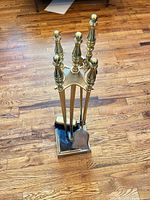 Full view of brass fireplace tool set on stand