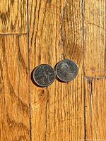 Two Canadian 25-cent coins on wooden surface, obverse and reverse visible