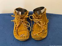 Front view of moccasins with laces and fringe visible