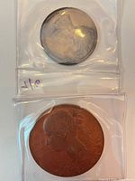 Both medals in protective flips, showing size comparison and general appearance