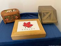 Three containers on table: carved floral box, Canada box, plastic storage box