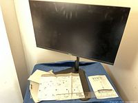 Front view of Dell monitor on stand with manuals and base visible