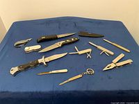 All 11 knives and tools laid out on blue cloth