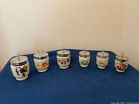 Front view of all six egg coddlers showing size comparison and motifs