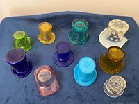 Ten assorted coloured glass top hats on cloth