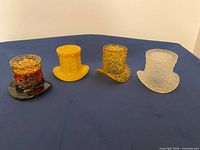 Front view of four miniature top hats showing colours and pattern