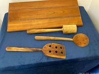 cutting board and three wooden utensils laid on blue surface