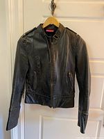 Front view of black leather jacket hanging on door