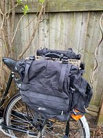 Pair of black MEC panniers mounted on bicycle rack, rear view