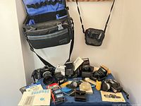 Overall view of cameras, flashes, bags, film and accessories on table