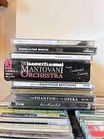Stack of CDs showing titles including Guerrilla Funk Monster, Mantovani Orchestra, Righteous Brothers, Tenors, Phantom of the Opera