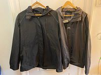 Both raincoats hanging on hangers front view