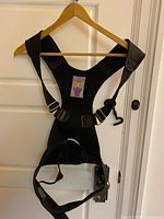 Front view of black adjustable posture corrector vest on hanger