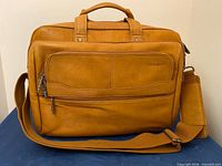 Front view showing leather texture, front zip pocket, shoulder strap