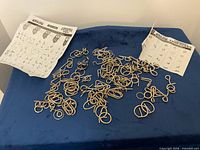 Group of brass-tone metal wire puzzles scattered on surface; answer-key sheets visible