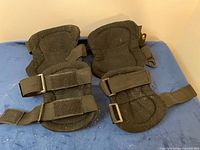 Rear view of four black pads showing straps and Velcro