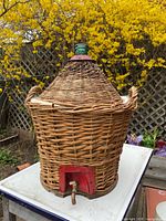front view of wicker-cased carboy showing copper spigot
