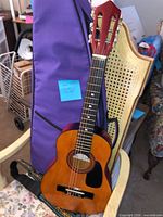 Guitar leaning on chair with gig bag and strap visible