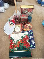 group shot of holiday tins, linens, felt Santa hanger, book, potpourri and box
