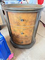 Front view showing three drawers, knobs and painted motif