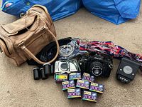Full lot showing camera, extra camera, flash, bag, film, canisters and strap