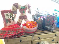 Overview of lot on dresser: tree skirt, candy canes, cookie cutter tub, boxed cards, clear tote of floral picks