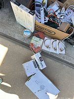 Lot overview showing extension cords, faucets boxes, towel rings, power strips, painter’s tape