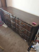 Front and side view of dresser showing nine drawers, brass pulls, finish, and wear