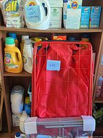 Red folding cart with fabric bag in front of shelf, blue lot sticker visible