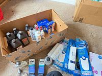 Overview of box with alcohol bottles, HP, nitrile gloves, insoles, shampoos, body wash and fragrance bottles