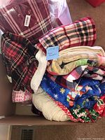 Box of assorted plaid and holiday throw blankets