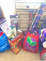 Overall view of two large gift bags containing wrapping paper rolls, bows and other supplies
