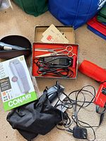 Overview showing Conair clipper box, Wahl clipper in pouch with charger, vintage clipper with scissors, red hair dryer