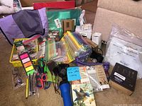 Overview of lot showing zip pouches, scissors, pens, sticky notes, flashlight, small books