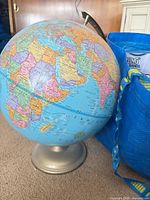 Freestanding globe next to blue tote; visible portion of lot