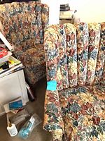 Both wingback armchairs side by side showing floral fabric and vertical tufting