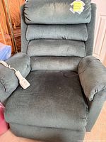 Front view of Pride dark green power lift recliner showing remote on arm and overall wear