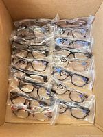 Fifteen packaged reading glasses arranged in shipping box