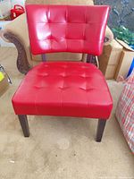 Front view of red tufted faux leather accent chair with dark wood legs