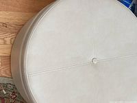 Top view of beige faux leather ottoman showing stitching and button detail