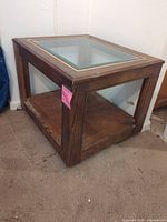 Overall view of square wooden end table with glass top and side panels