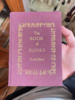 Front cover of maroon cloth hardcover with gold runic border and title