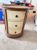 front view showing three cream drawers with floral motif and metal knobs